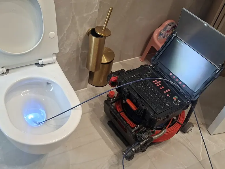 מצלמת צנרת מוחדרת לאסלה, ולידה מסך המערכת בחדר רחצה מעוצב